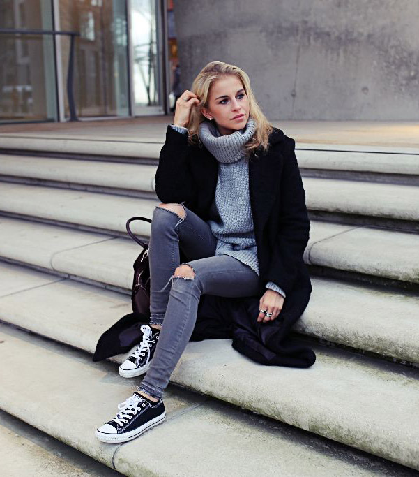 Caroline Daur is a vision in greyscale, wearing a pair of simple black and white converse with ripped grey jeans and a matching turtleeck to create an easy but sophisticated style. Sweater/Jeans: Review, Shoes: Converse, Bags: Aigner, Coat: Asos.