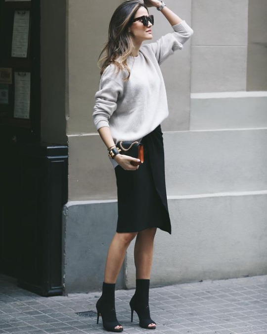 Alex Rivière is wearing an elegant black pencil skirt with a cream sweater and heeled open toe boots to create this spring style. Throw on a pair of shades to get this look! Bag: Sandro Paris.